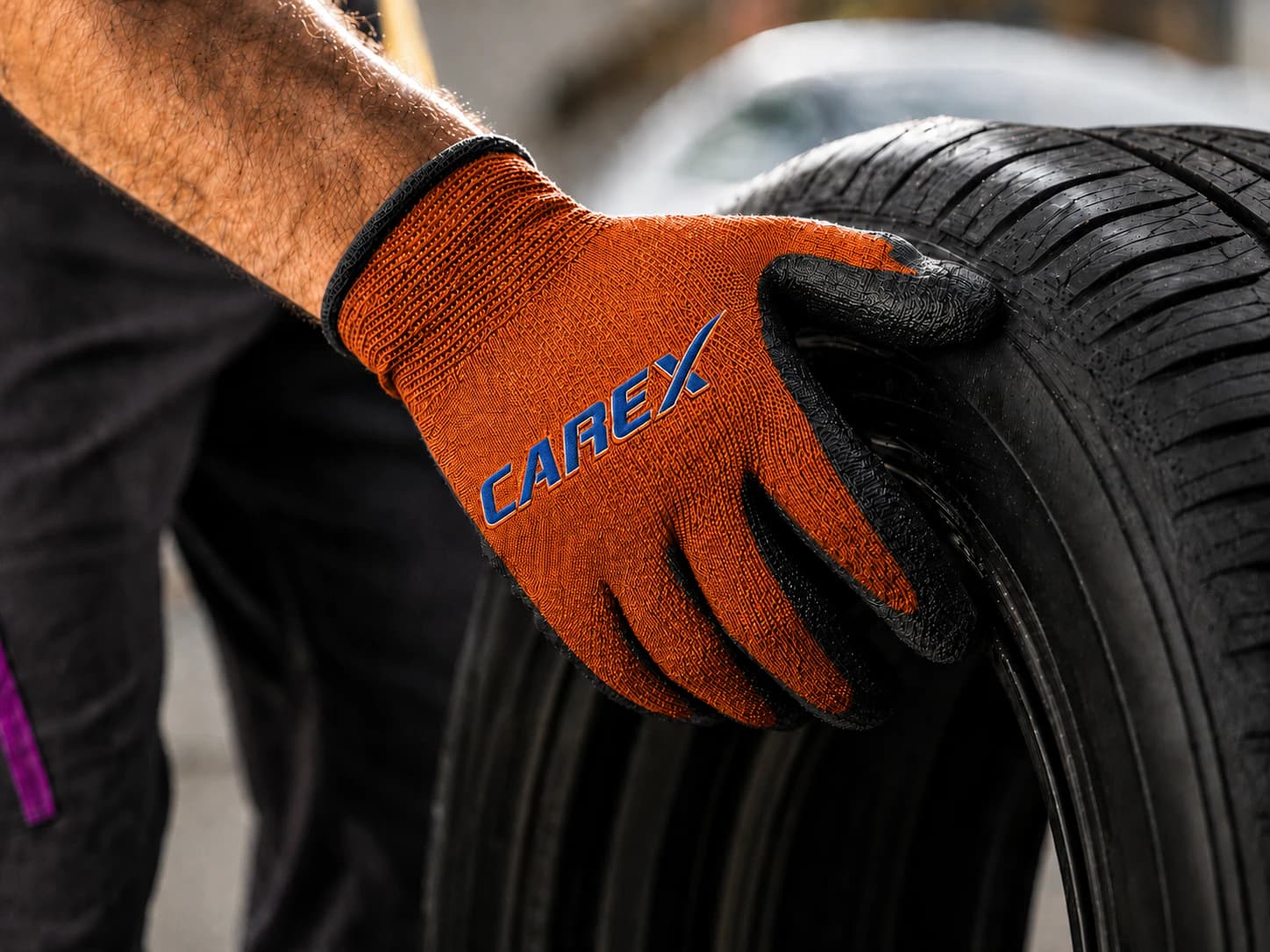 Carex Mechaniker hält einen Reifen mit orangefarbenem Arbeitshandschuh
